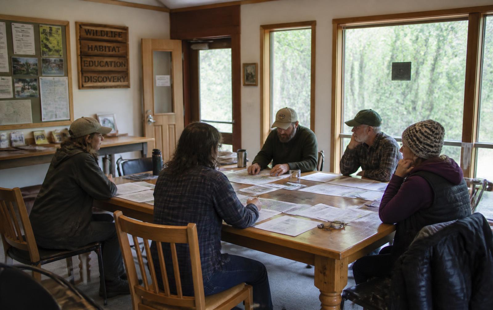 Staff and trustees reviewing printed plans and maps around a table in a meeting room.